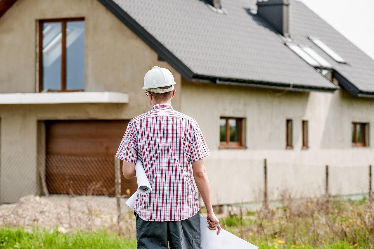 Home service contractor holding blueprints in front of a residential home